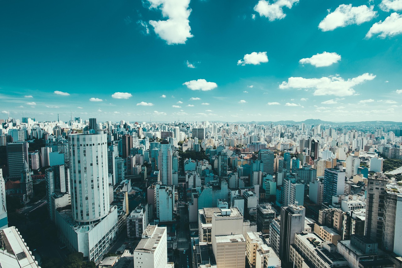 A zoomed-out view of an urban area with sky, clouds, and hills in the background.
